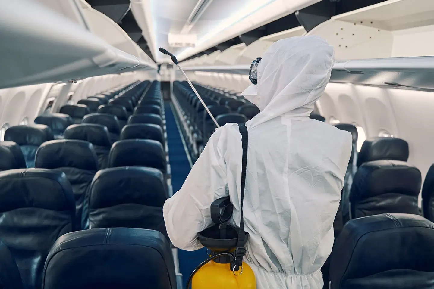 Technician applying residual disinsection treatment inside an aircraft cabin